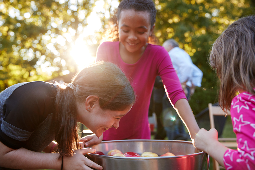 Children participating in a traditional bobbing-for-apples game, a popular Halloween activity.